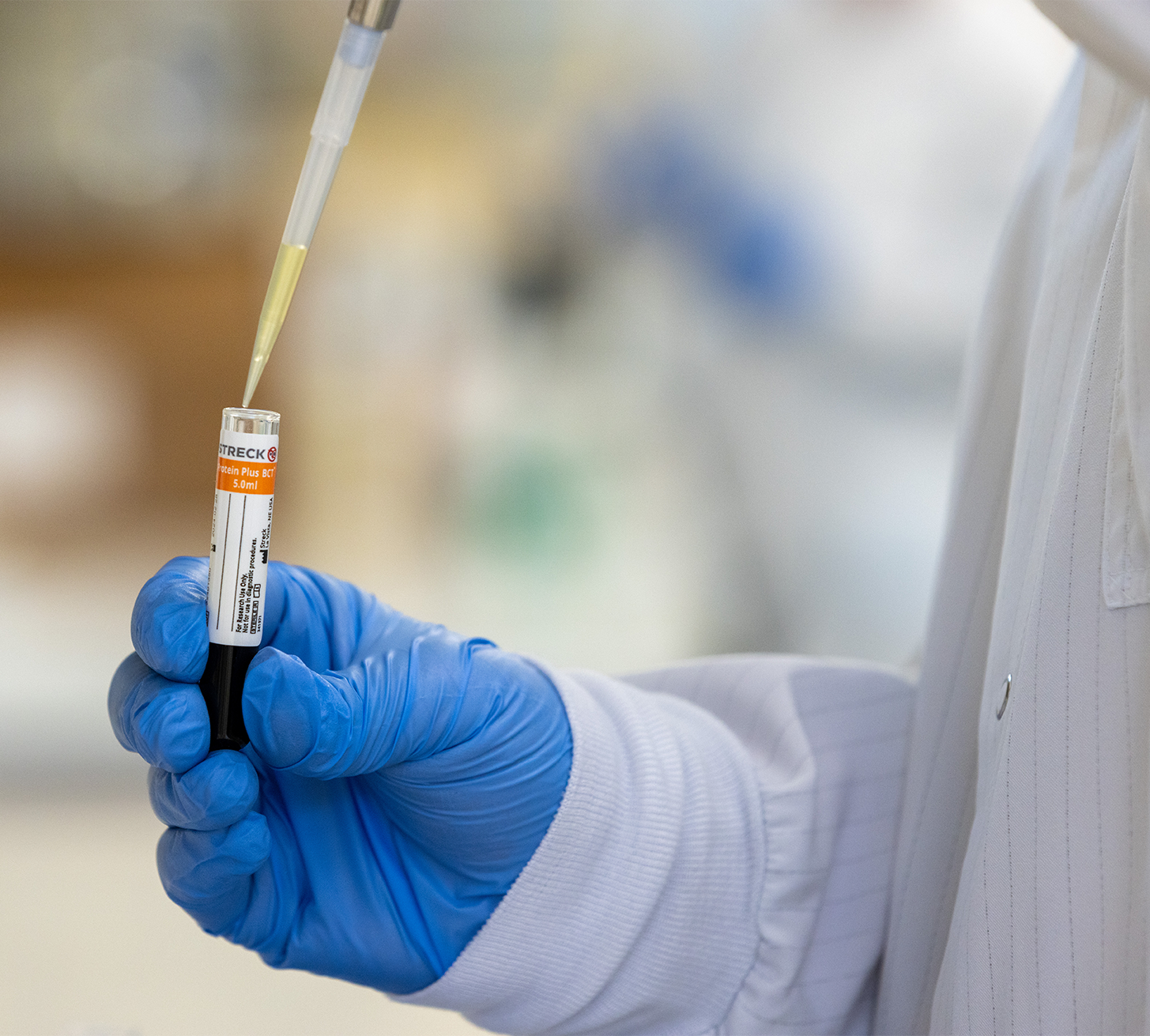 Pipetting from Protein Plus BCT while wearing rubber gloves in a lab